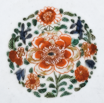 圖為清代五彩花卉紋碟細節(jié)圖，碟心主題紋飾為團花圖，紅花綠葉，相映成趣。（來源：廣州十三行博物館）